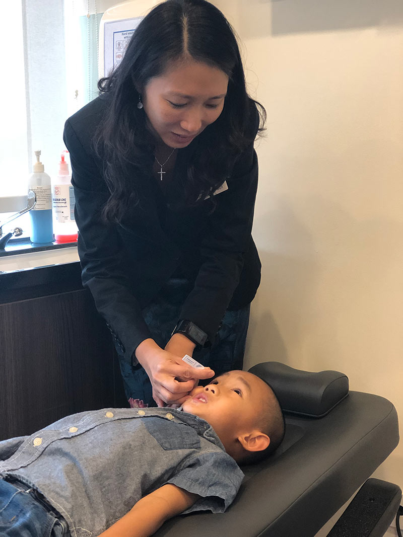 Dr Cheryl Ngo administering cycloplegic eye drops to a child before performing cyclorefraction